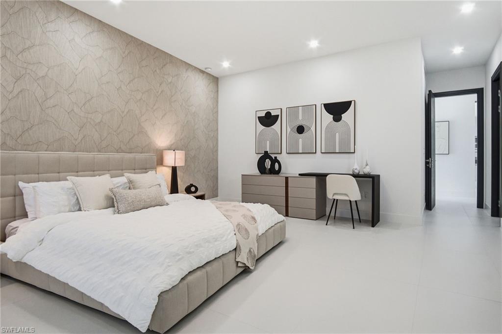 Spacious bedroom featuring recessed lighting, a decorative accent wall, light-toned flooring, and dark-framed interior doors