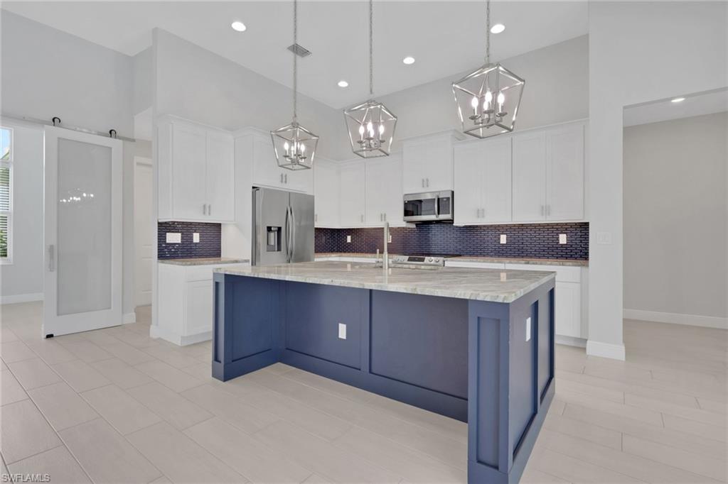 Island kitchen with granite counters, classic white shaker style cabinets with crown molding and crown molding.