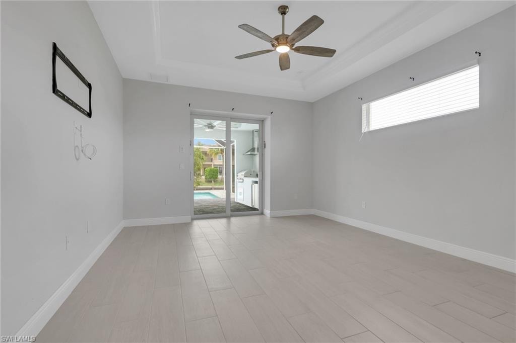 Owner's bedroom with tray ceiling, transom window for natural light, pool/lanai access through sliding glass doors.