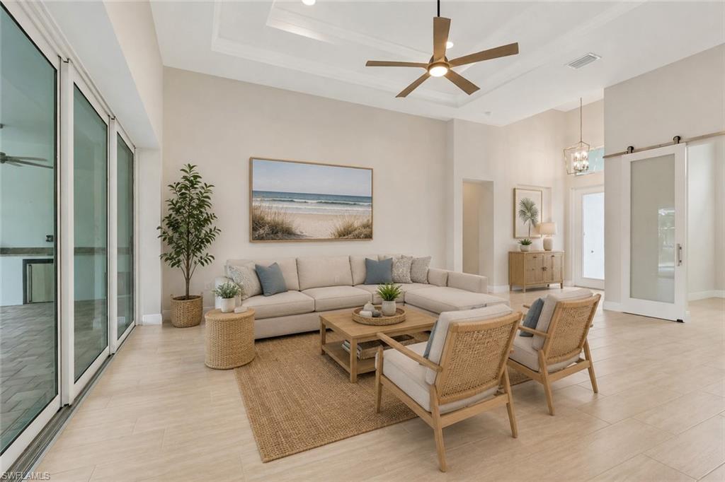 Living room with trey ceiling overlooking the lanai and pool through pocketing sliding glass doors