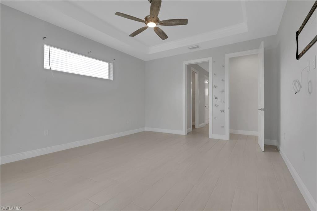 Owner's bedroom with tray ceiling, transom window for natural light, pool/lanai access through sliding glass doors.