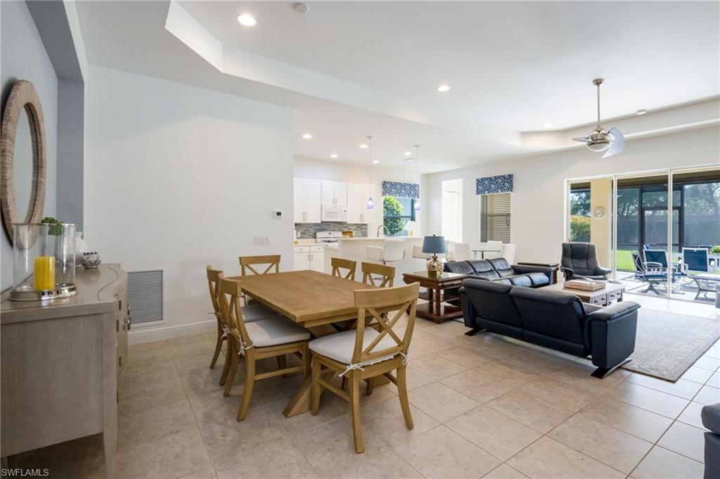 Open-concept living space featuring neutral tile flooring, recessed lighting, and a tray ceiling with a modern ceiling fan