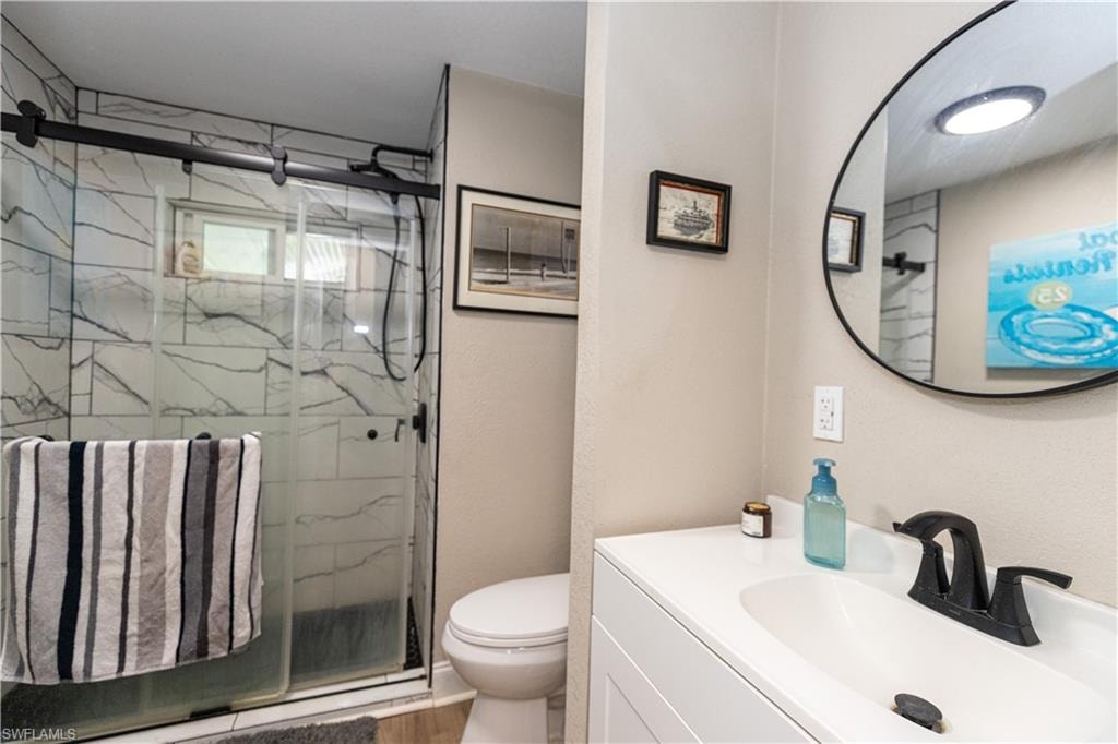 Bathroom featuring a walk-in shower with a sliding glass door and marble-look tile surround