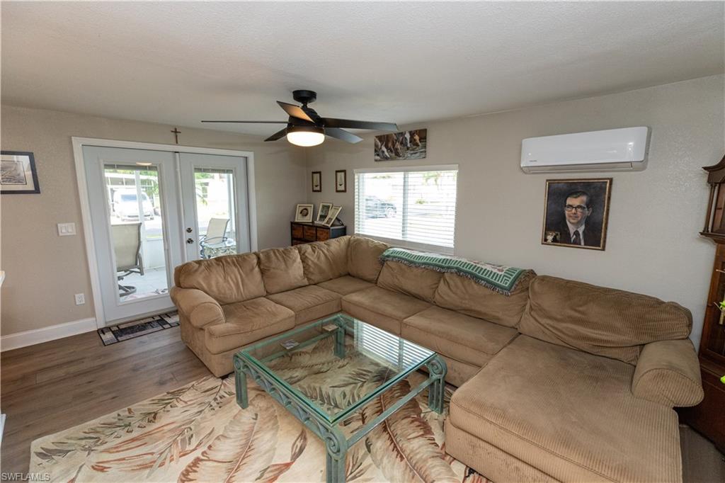 Living area featuring wood-finish flooring, light neutral wall paint, and a ceiling fan with integrated lighting
