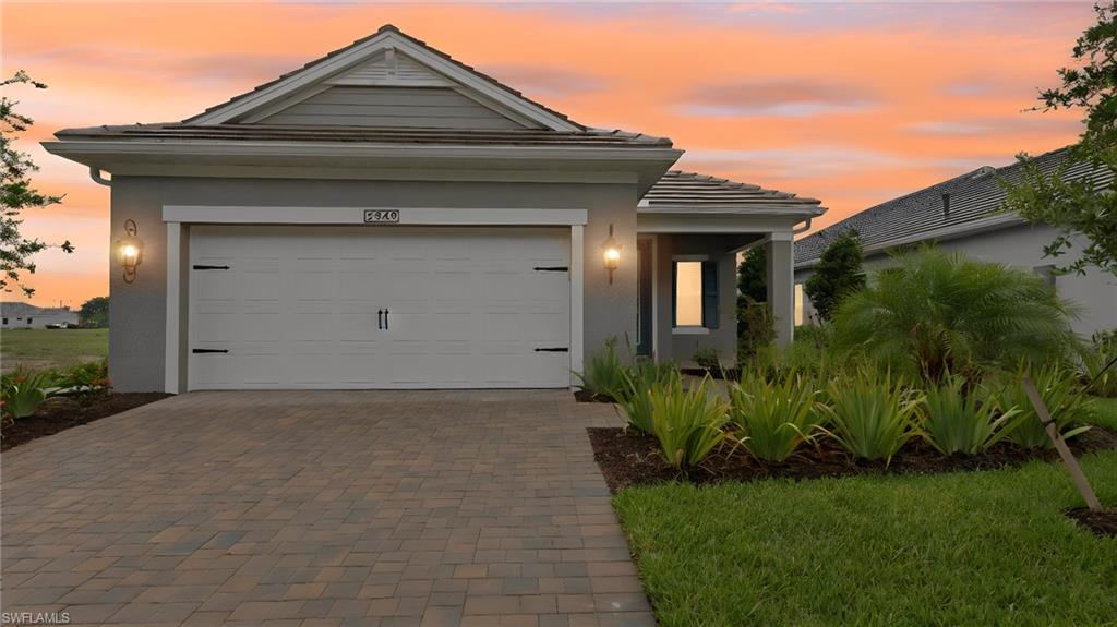 Contemporary single-story exterior featuring a paver driveway, an attached garage with decorative hardware, and a covered entryway