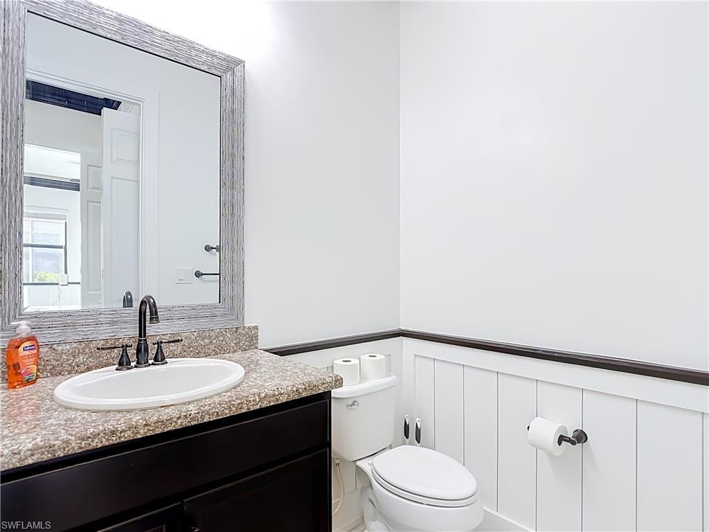 Bathroom featuring a black vanity with a granite-style countertop, white oval sink, and matte black faucet