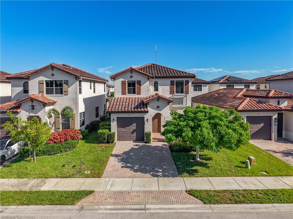 Mediterranean-style residence featuring a tile roof, stucco exterior, decorative shutters, a paver driveway, and an arched entry