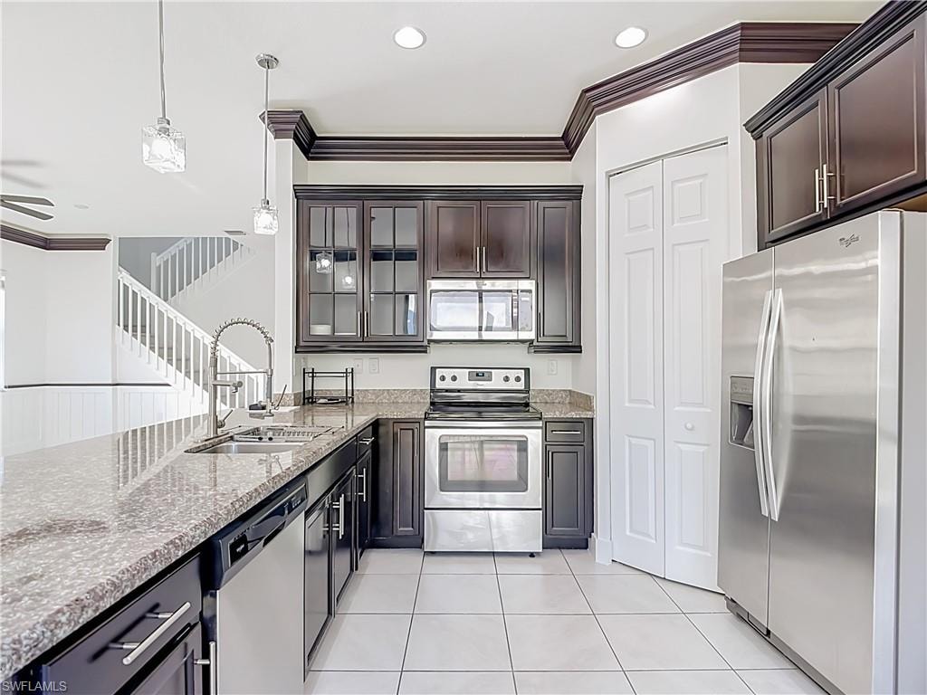 Kitchen featuring dark wood cabinetry, light-colored granite countertops, and stainless steel appliances