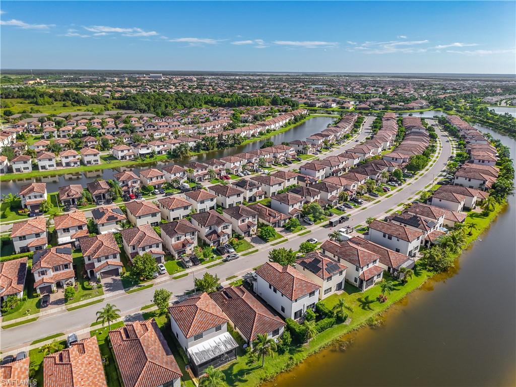 Residential development featuring numerous homes with terracotta tile roofs, a winding street, and waterfront access to interconnected canals