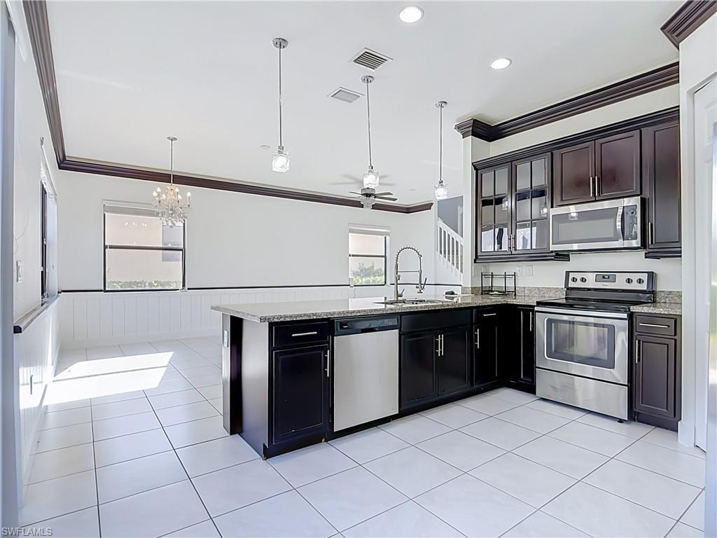 Kitchen featuring dark wood cabinetry, stainless steel appliances, and a granite-topped island