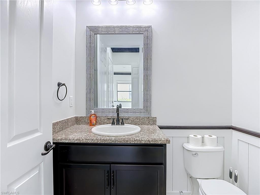 Bathroom vanity featuring a dark wood-finish cabinet with a light-colored countertop, an undermount sink, and a dark-finished faucet