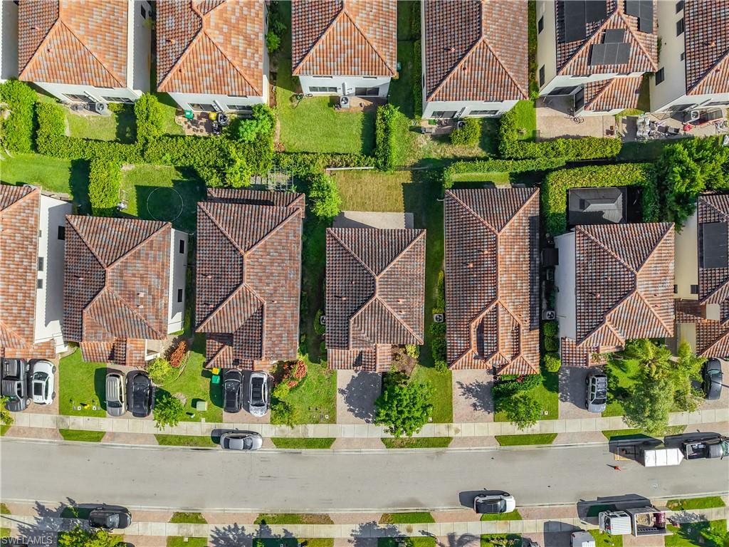 Residential street featuring multiple properties with terracotta tile roofs, paved driveways, and manicured landscaping