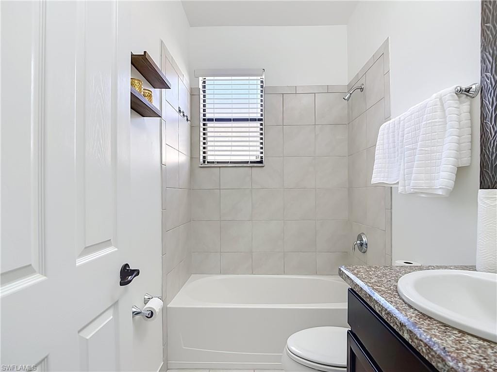 Bathroom featuring a white tub, tiled shower surround, and a window with blinds