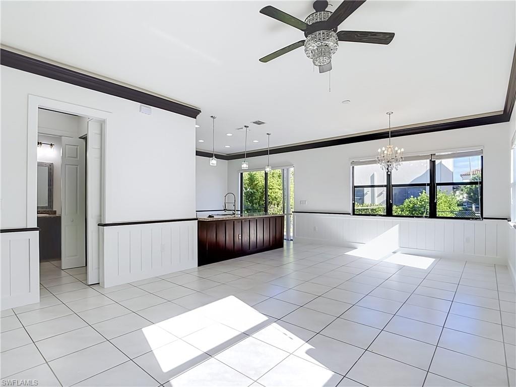 Spacious interior featuring white tile flooring, dark wood crown molding, and white wainscoting