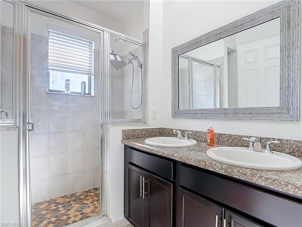 Bathroom featuring a dual vanity with granite-finish countertop, dark wood cabinetry, and chrome fixtures