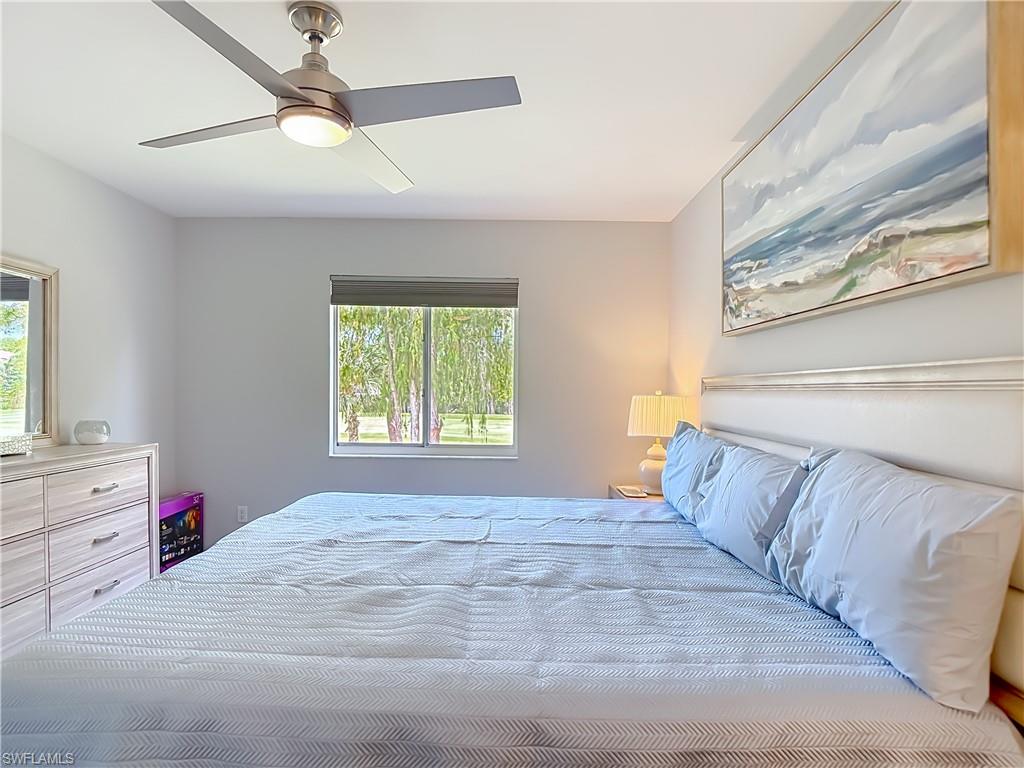 Bedroom featuring a ceiling fan with integrated lighting, a window with exterior views, and neutral wall tones