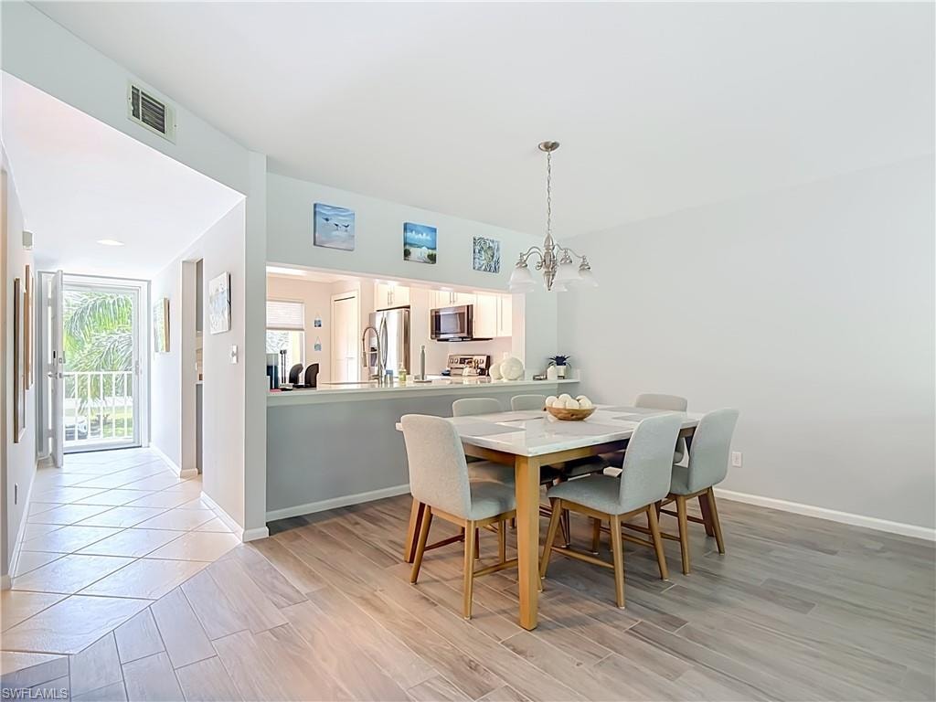 Dining area featuring wood-look tile flooring and a multi-light chandelier