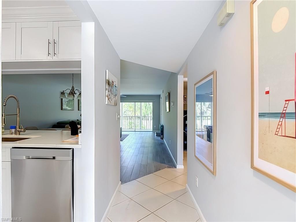 Kitchen featuring stainless steel appliances, white cabinetry with crown molding, white tile flooring, a built-in pantry, and a window with pleated blinds