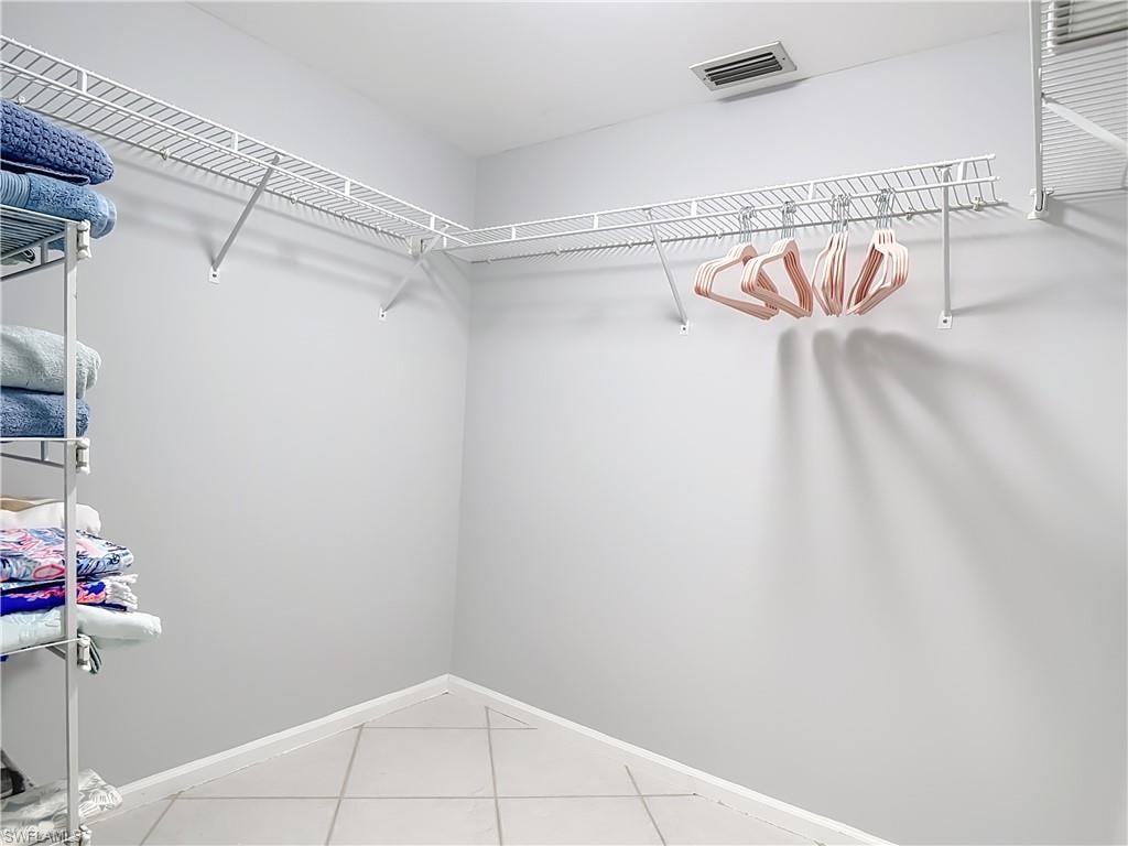 Walk-in closet featuring light gray walls, white wire shelving, a hanging rod, and light tile flooring