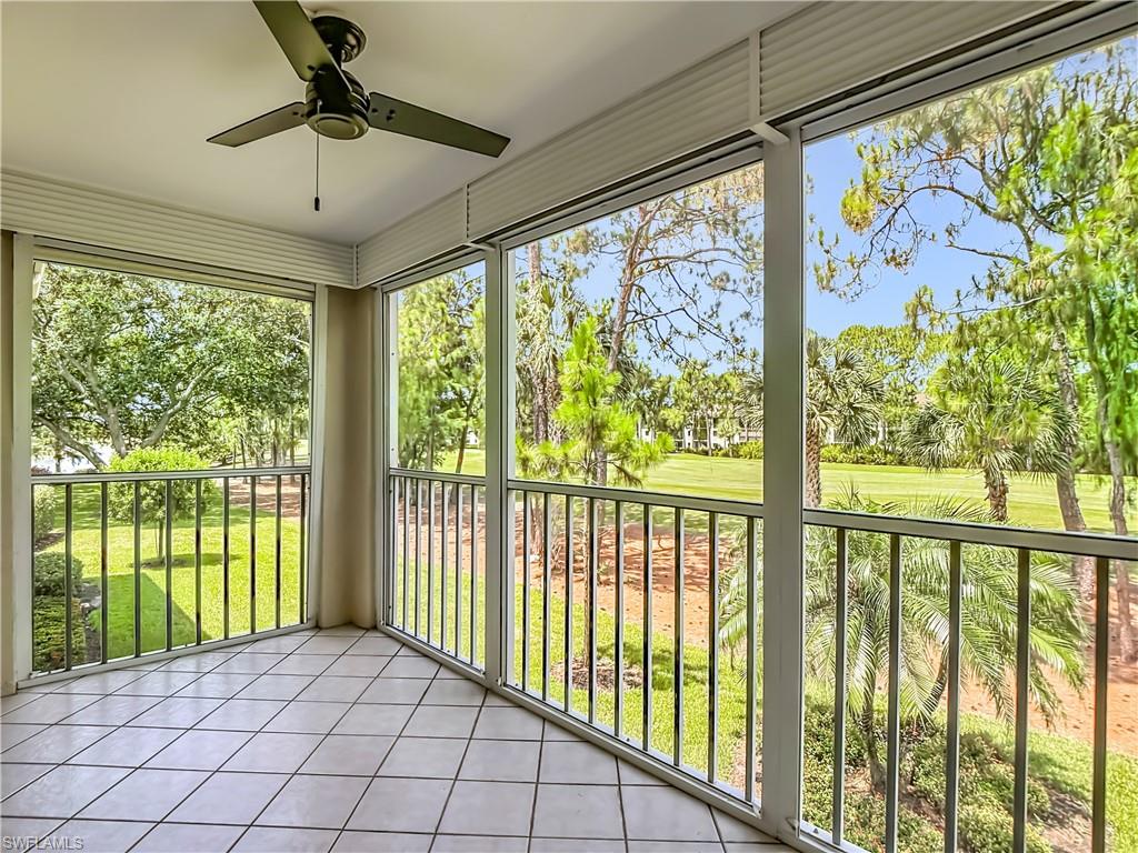 Screened porch featuring tiled flooring, a ceiling fan, and expansive outdoor scenery with mature trees and green areas