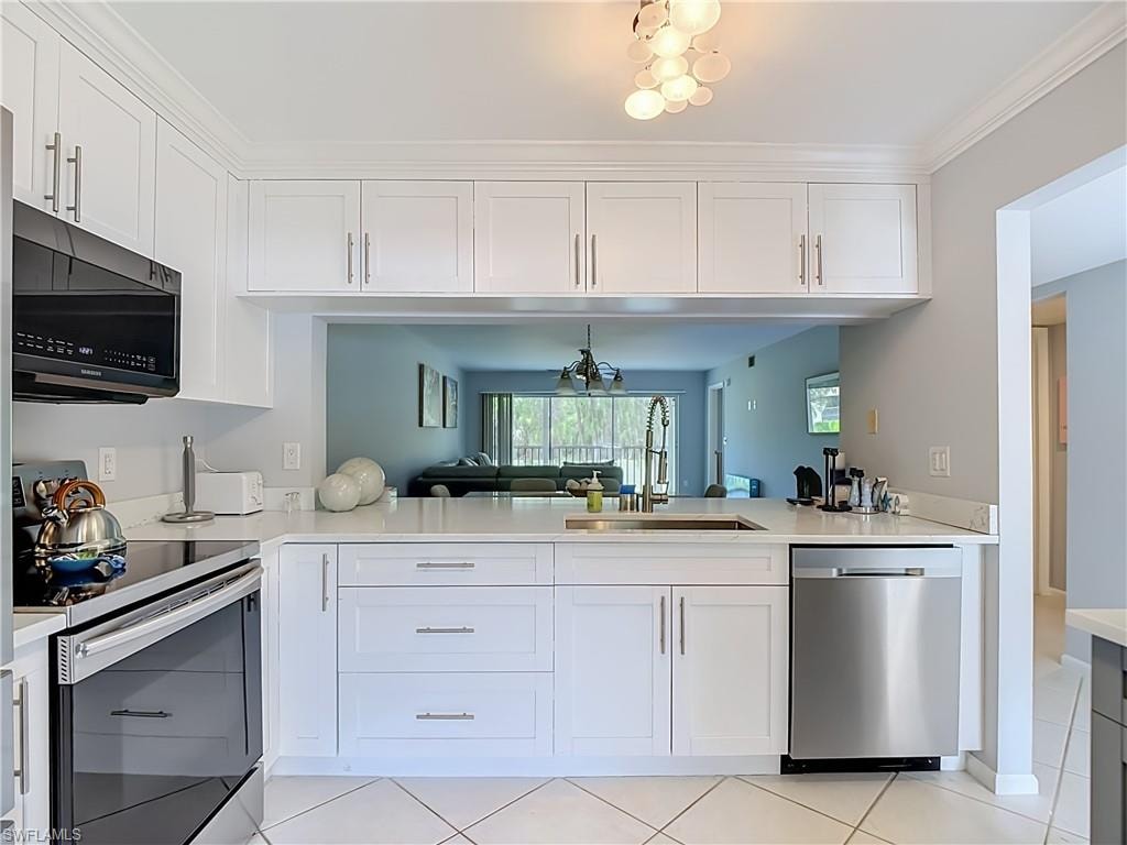Modern kitchen featuring white shaker cabinetry with brushed nickel hardware, quartz countertops, a stainless steel dishwasher, and a black built-in microwave