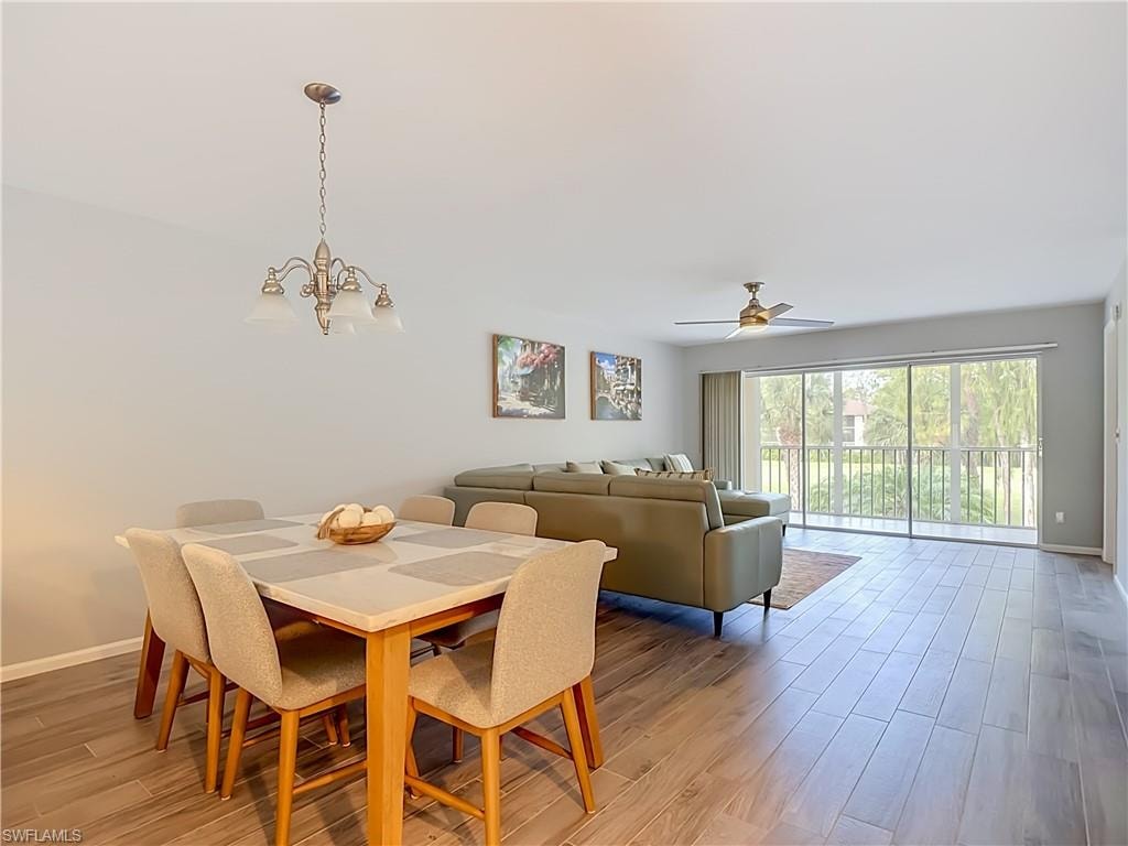 Open-concept living area featuring wood-finish flooring, a contemporary ceiling fan, and large sliding glass doors leading to an outdoor space with white railing