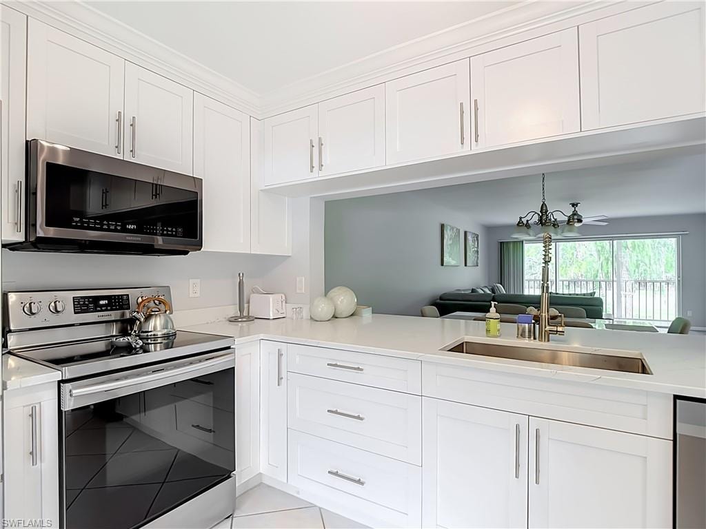 Modern kitchen featuring white shaker cabinetry, stainless steel appliances, a stainless steel sink with a gooseneck faucet, and light-toned countertops