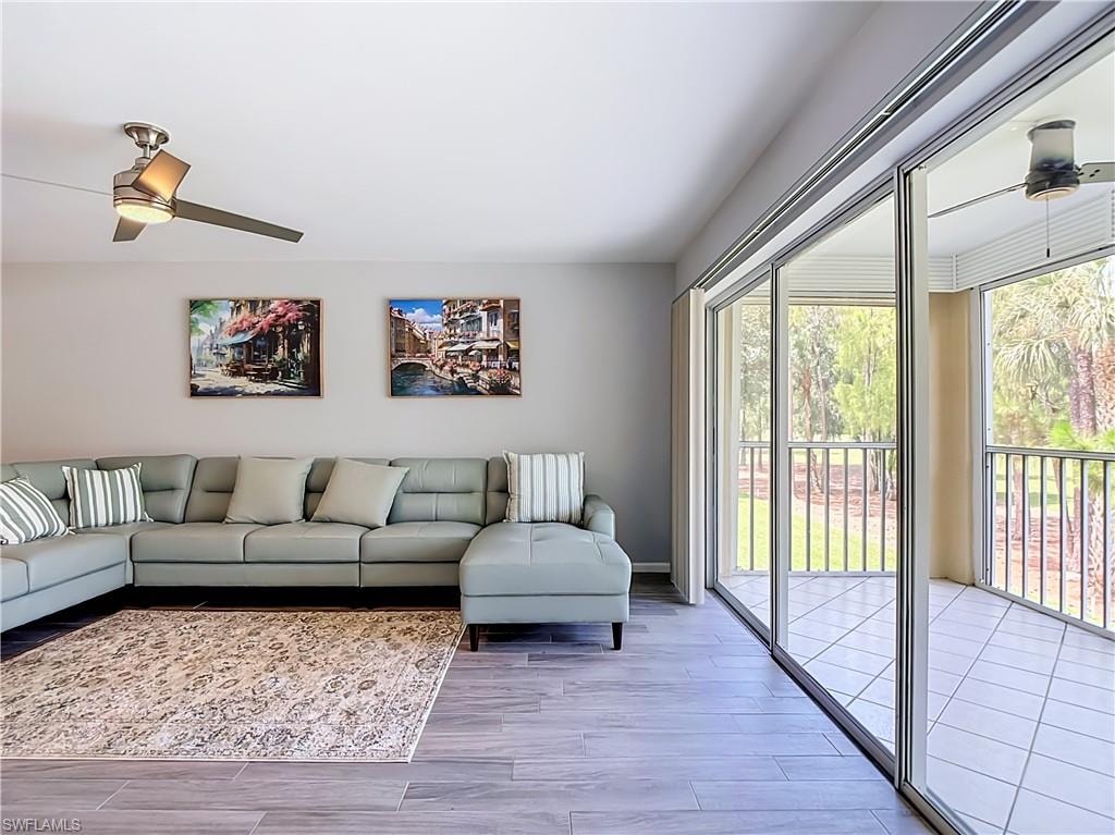 Living space featuring wood-finish flooring, a contemporary ceiling fan, and sliding glass doors opening to an enclosed balcony