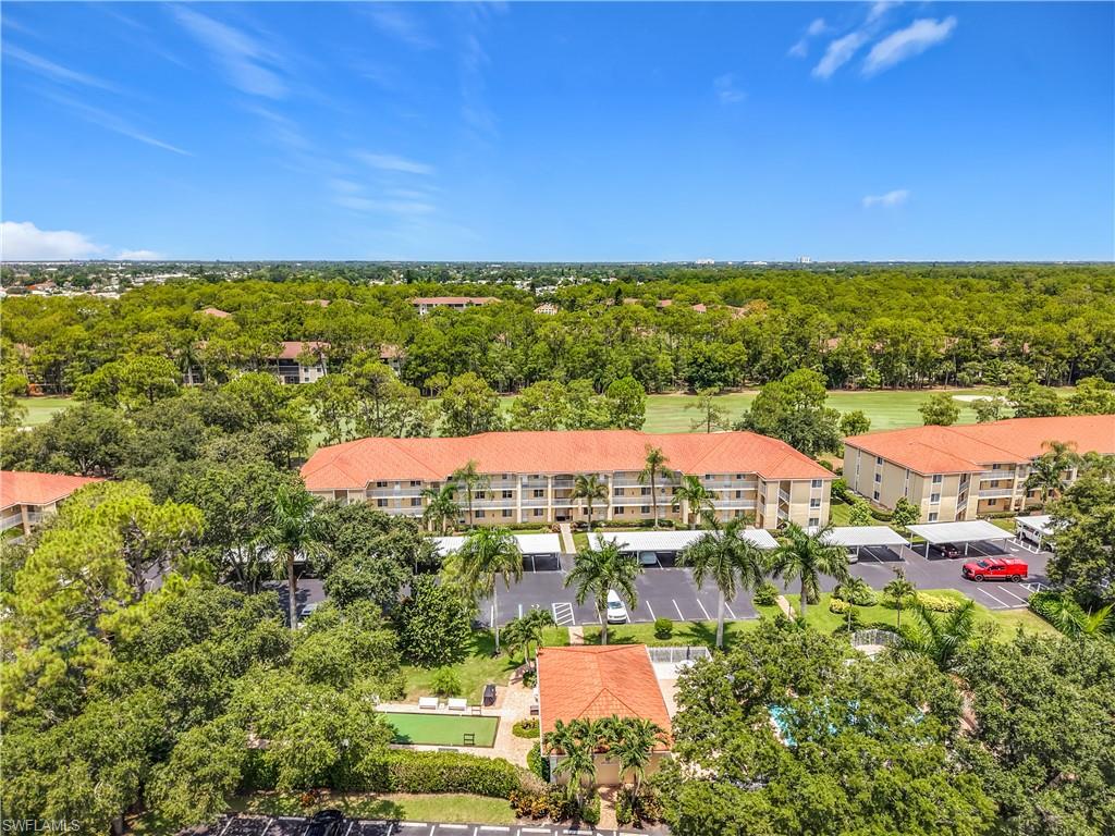 Aerial perspective highlighting multiple residential buildings with terracotta-style roofs, surrounded by extensive mature trees