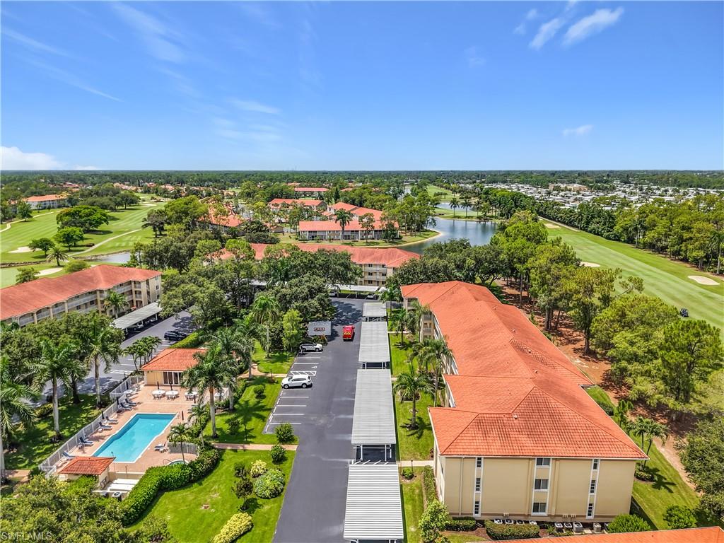 Expansive aerial perspective showcasing multiple residential buildings with terracotta-style roofing, surrounded by lush green landscaping
