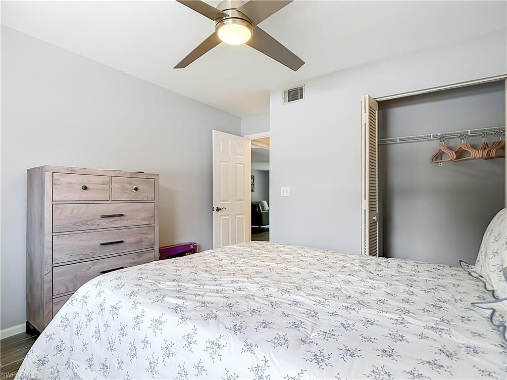 Bedroom featuring light grey wall paint, wood-finish flooring, and a ceiling fan with integrated lighting