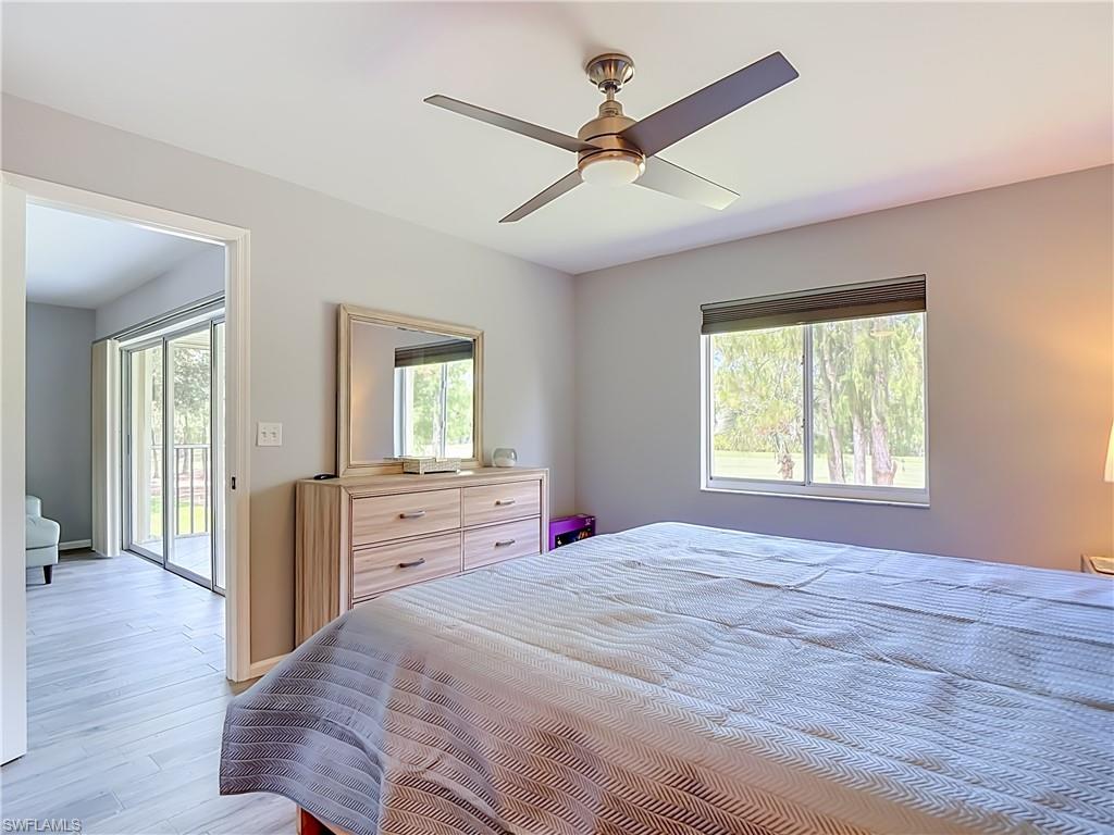 Bedroom featuring light gray walls, a window with a dark roller shade, and a ceiling fan with integrated lighting
