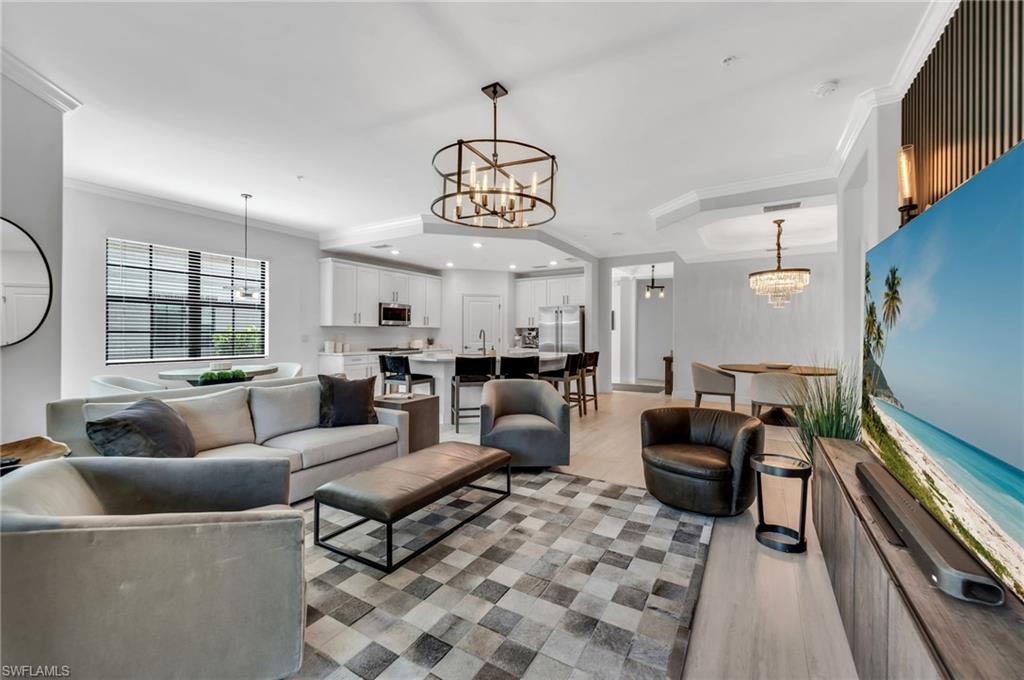 Open-concept living space featuring wood-finish flooring and crown molding