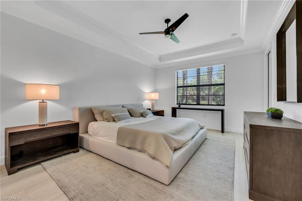 Spacious room featuring a tray ceiling, crown molding, and large window with horizontal blinds
