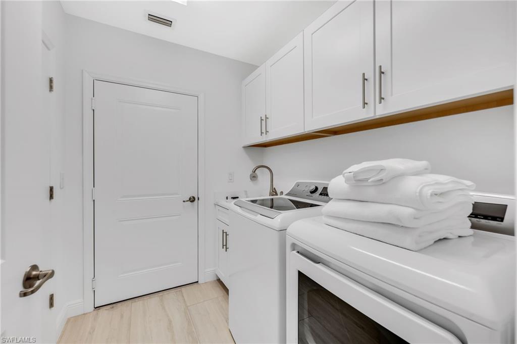 Dedicated laundry area featuring white shaker-style cabinetry, a built-in utility sink with a brushed nickel faucet, and wood-finish flooring