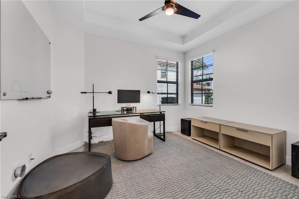 White walls, two windows with horizontal blinds, and a tray ceiling with a ceiling fan