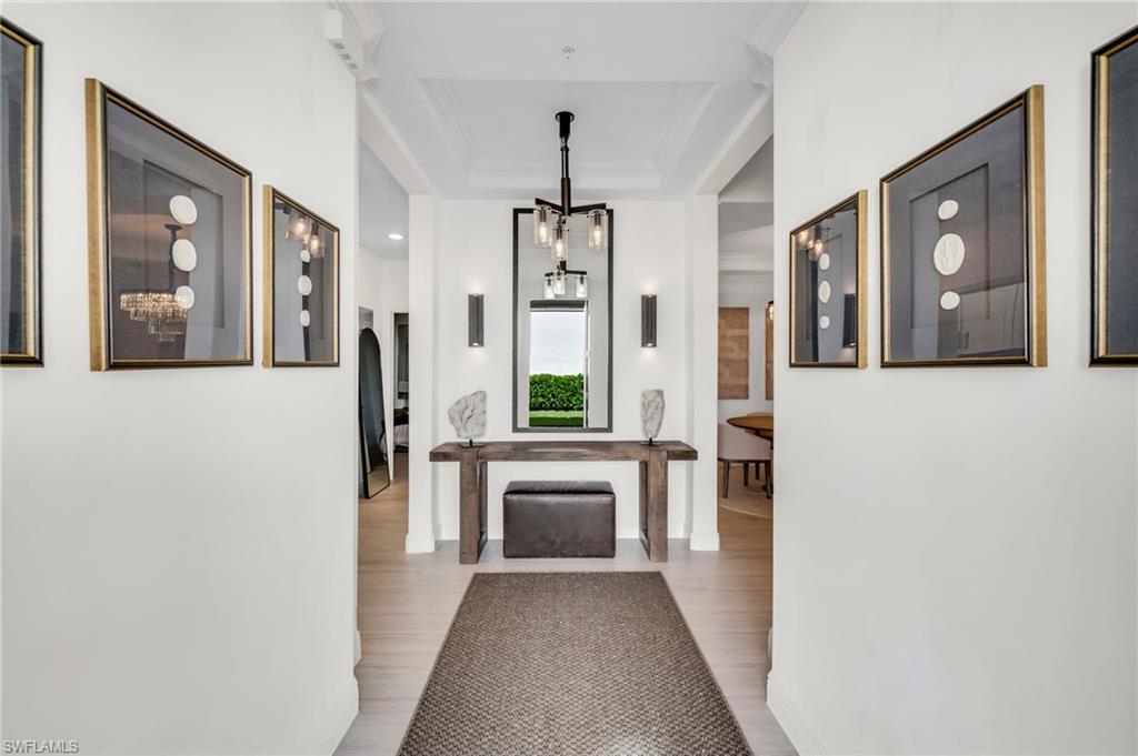 Foyer featuring crown molding, hardwood-style flooring, and a contemporary chandelier
