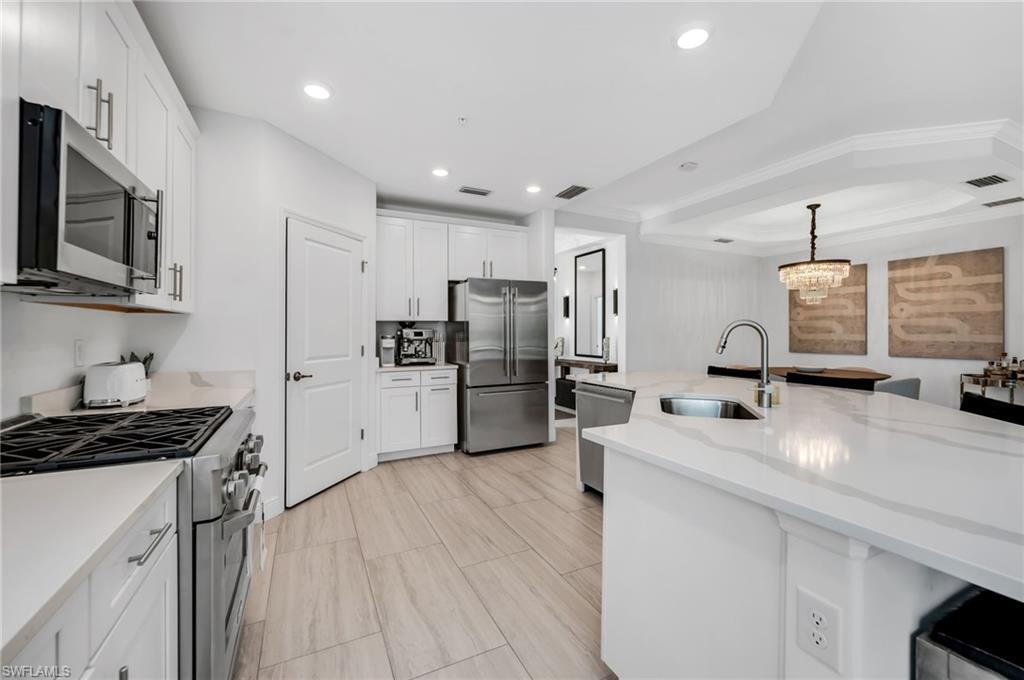 Modern kitchen featuring white cabinetry, stainless steel appliances, light wood-finish flooring, a large island with an undermount sink, and recessed lighting
