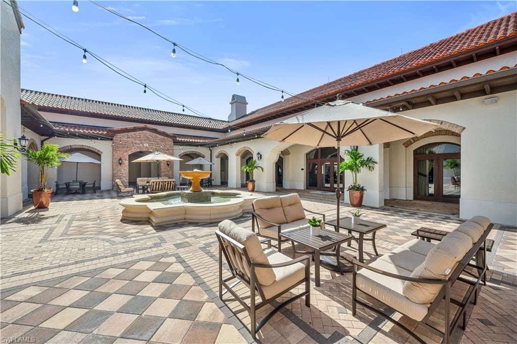 Expansive courtyard featuring a patterned paver patio, a multi-tiered fountain, and string lighting