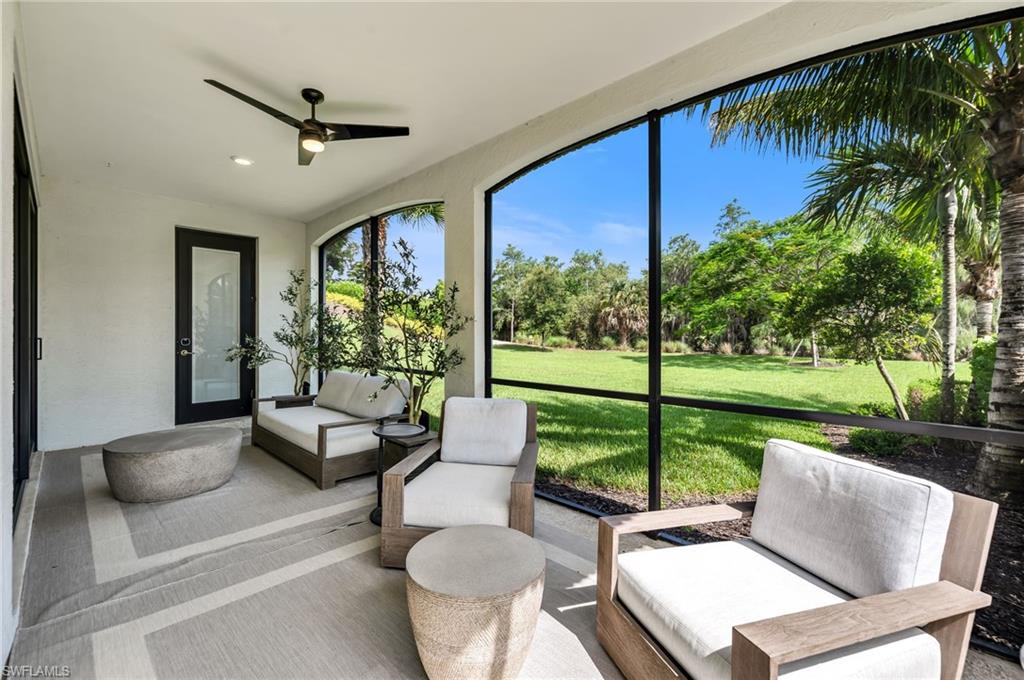Expansive screened patio featuring a ceiling fan, recessed lighting, a modern black-framed glass door, and a manicured lawn beyond