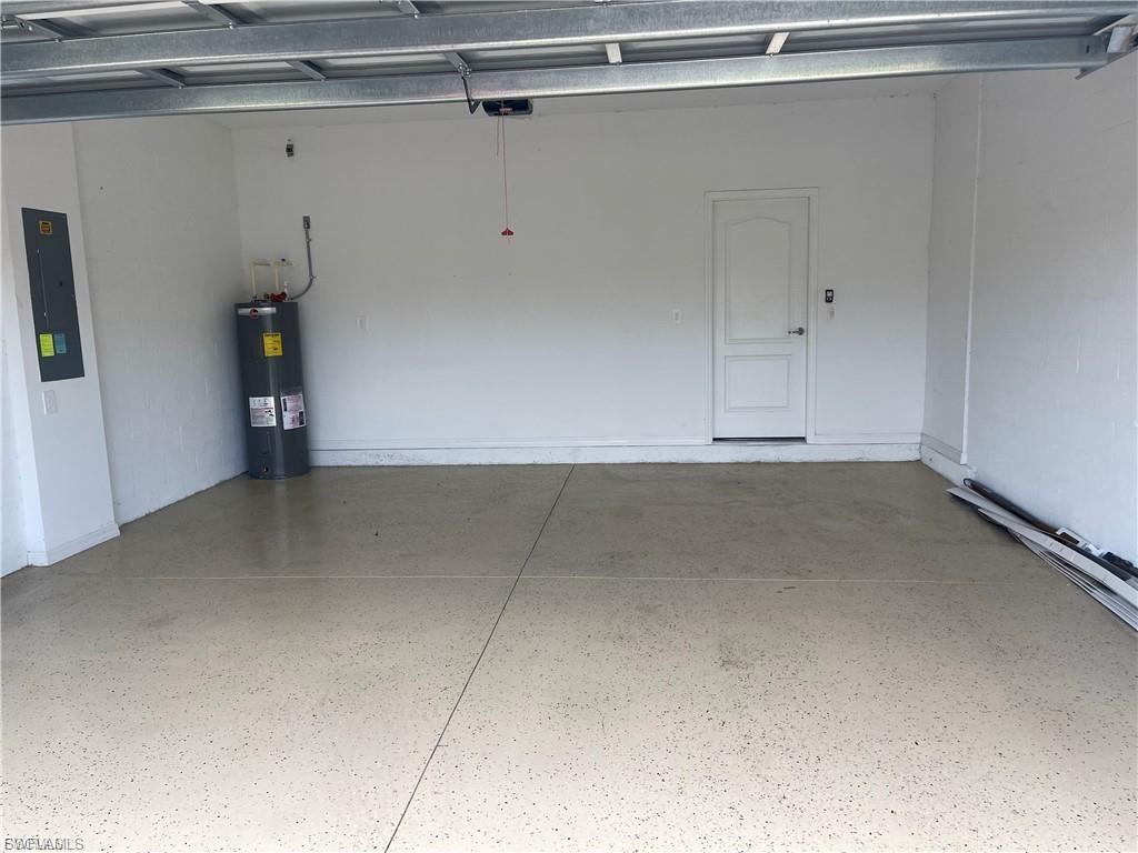 Spacious garage featuring white painted walls, a textured light-toned epoxy floor, and a white interior door with a paneled design