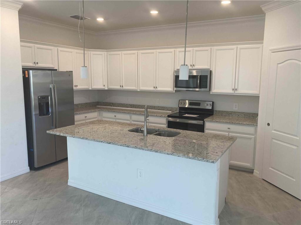 Kitchen featuring an island, light-toned cabinetry, stainless steel appliances, and granite countertops
