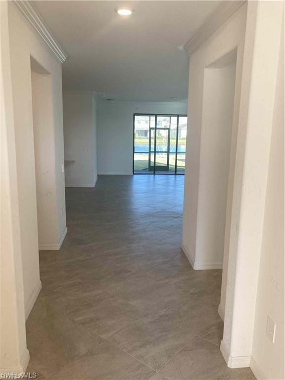 Open concept interior featuring large format tile flooring and crown molding