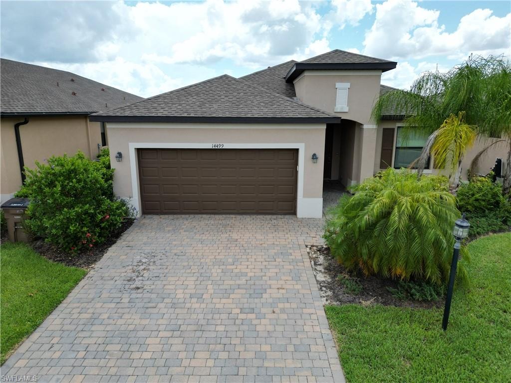 Stucco exterior with a two-car garage and paver driveway