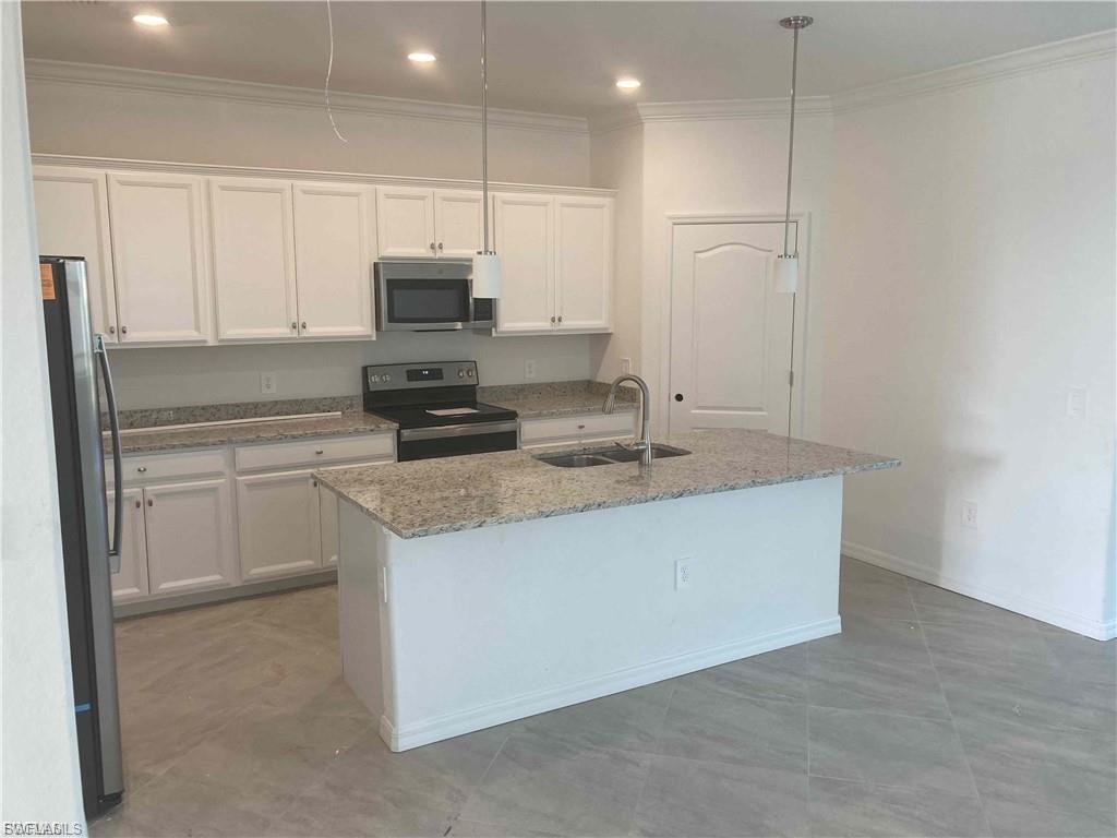 Modern kitchen featuring an island with a double basin sink, white cabinetry, granite countertops, and stainless steel appliances