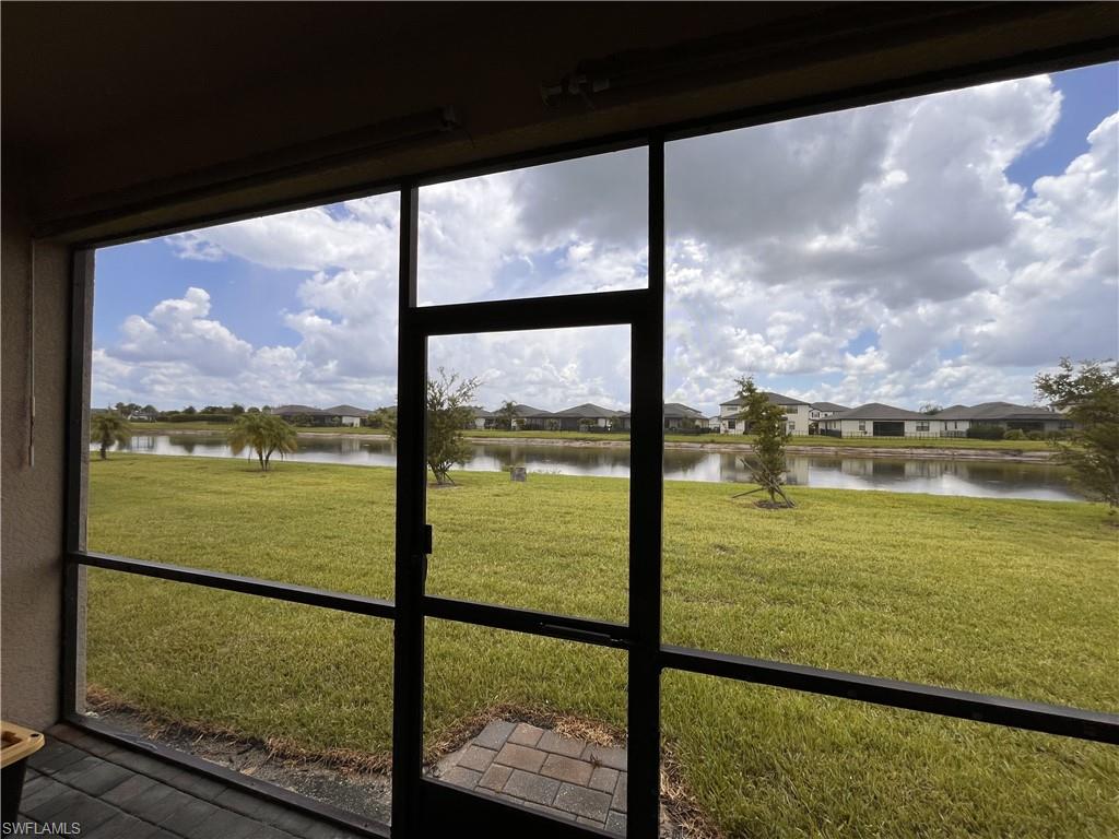 Screened patio with a paver landing and a water feature beyond a manicured lawn