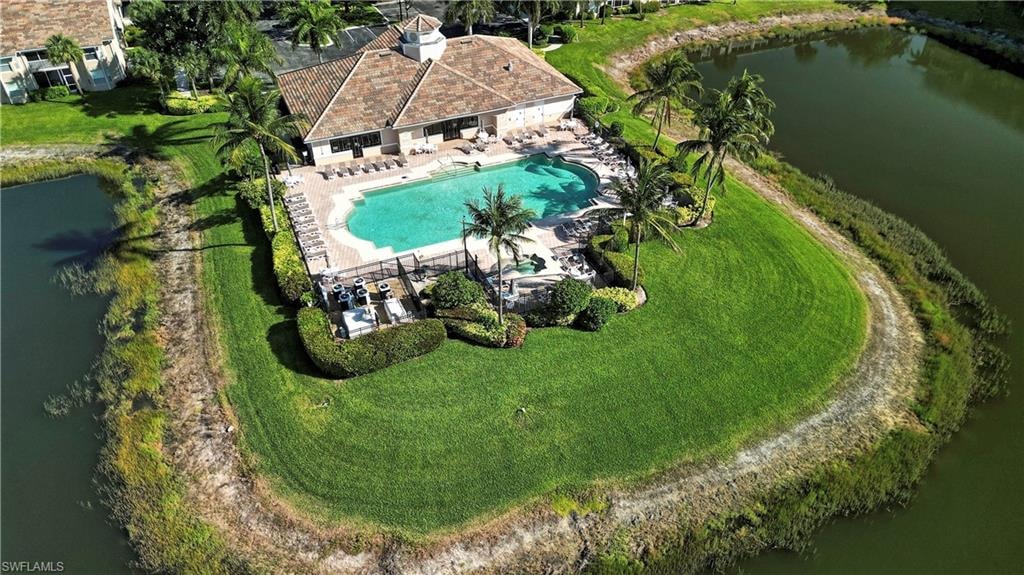 Resort-style pool area featuring an irregular-shaped pool, surrounding sun deck, mature palm trees, and manicured landscaping