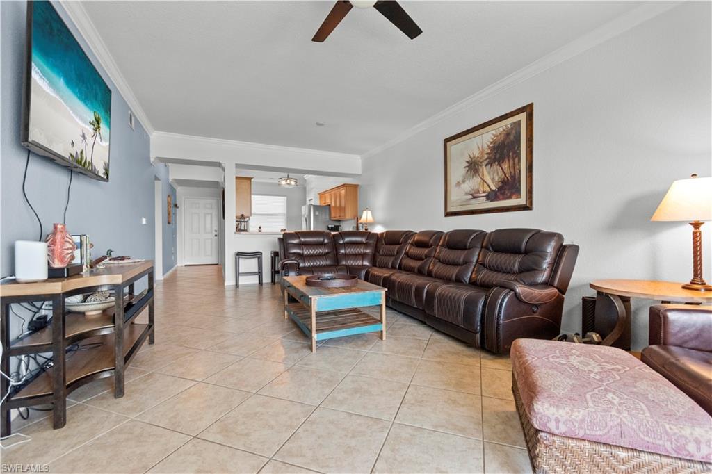Spacious living area featuring tile flooring on the diagonal and crown molding.