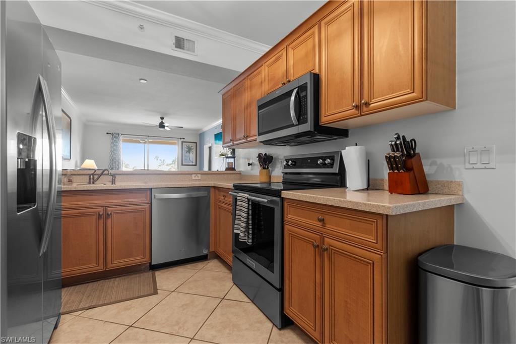 Kitchen featuring wood cabinetry, stainless steel appliances, light-toned countertops, and tile flooring