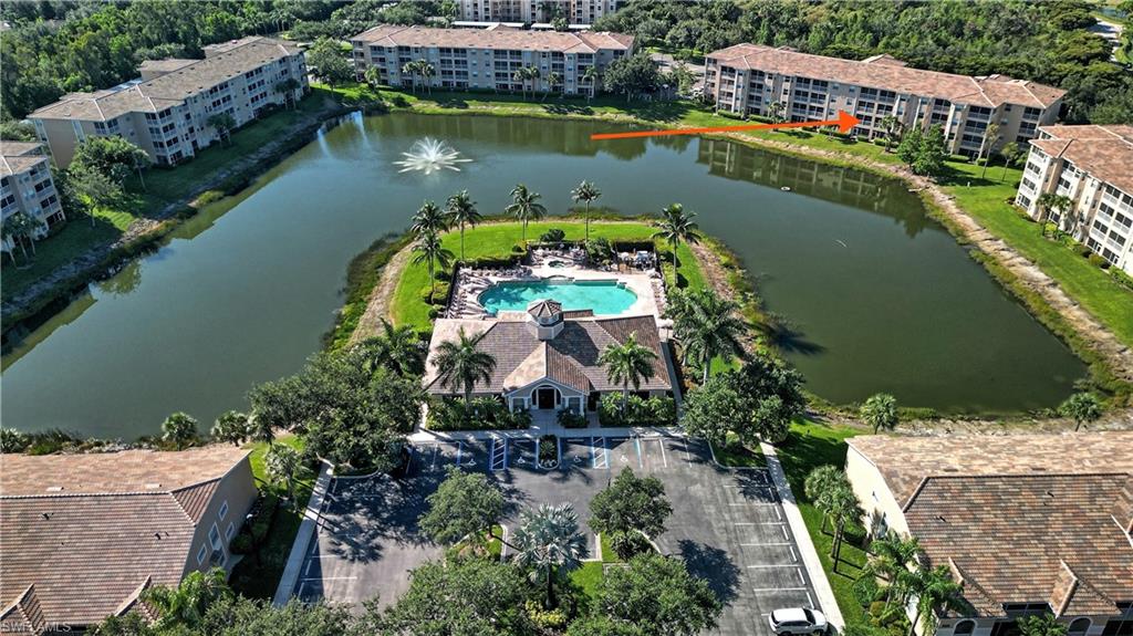Community featuring a central recreational building, a large swimming pool with ample lounge seating, and a water feature